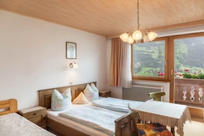 Une chambre à coucher comprenant un lit, des tables de chevet, une chaise, une table, une fenêtre avec vue et un luminaire au plafond.