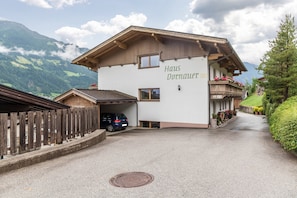 Un bâtiment appelé « Haus Dornauert », doté d’une façade en bois, d’un garage et d’une allée menant à un point de vue sur la montagne.