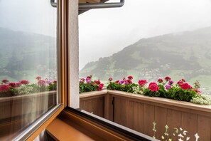 Ein Balkon mit Holzbalkonen und Blumenkästen mit rosa und weißen Blumen.