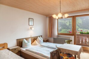 A bedroom with a bed, bedside tables, a chair, a table, a window with a view, and a ceiling light. - Apartment 'Dornauer' with Mountain View, Balcony & Wi-Fi (Hippach)
