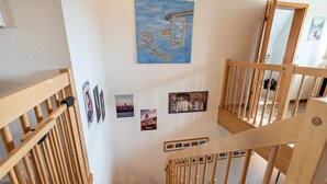 A wooden staircase with a handrail, a painting of a cityscape, and several framed photographs on the wall. - Apartment Krakow am See with Terrace & Wi-Fi (Krakow am See)