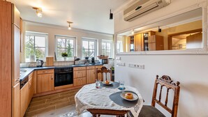 A kitchen with wooden cabinets, a dining table with chairs, and a large window. - Apartment Krakow am See with Terrace & Wi-Fi (Krakow am See)
