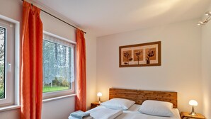 Une chambre à coucher avec une tête de lit en bois, deux tables de chevet avec des lampes, une fenêtre avec des rideaux et un tableau encadré au mur.