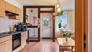 Une cuisine avec des meubles de rangement en bois, une cuisinière et un coin repas comprenant une table et des chaises.