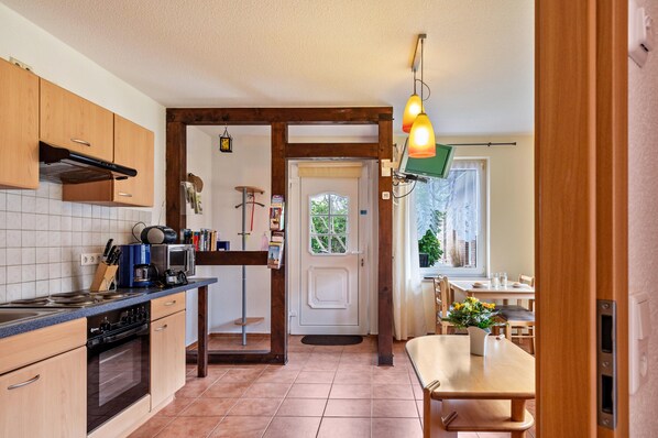 Una cocina con armarios de madera, una estufa y un comedor con una mesa y sillas.