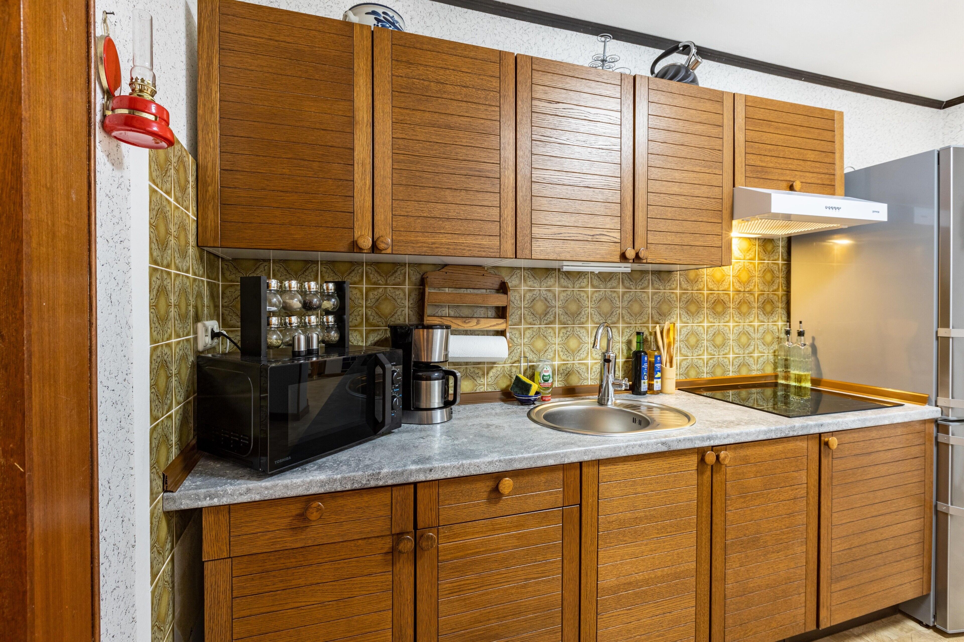 A kitchen with wooden cabinets, a stainless steel sink, a microwave, a coffee maker, and a refrigerator.