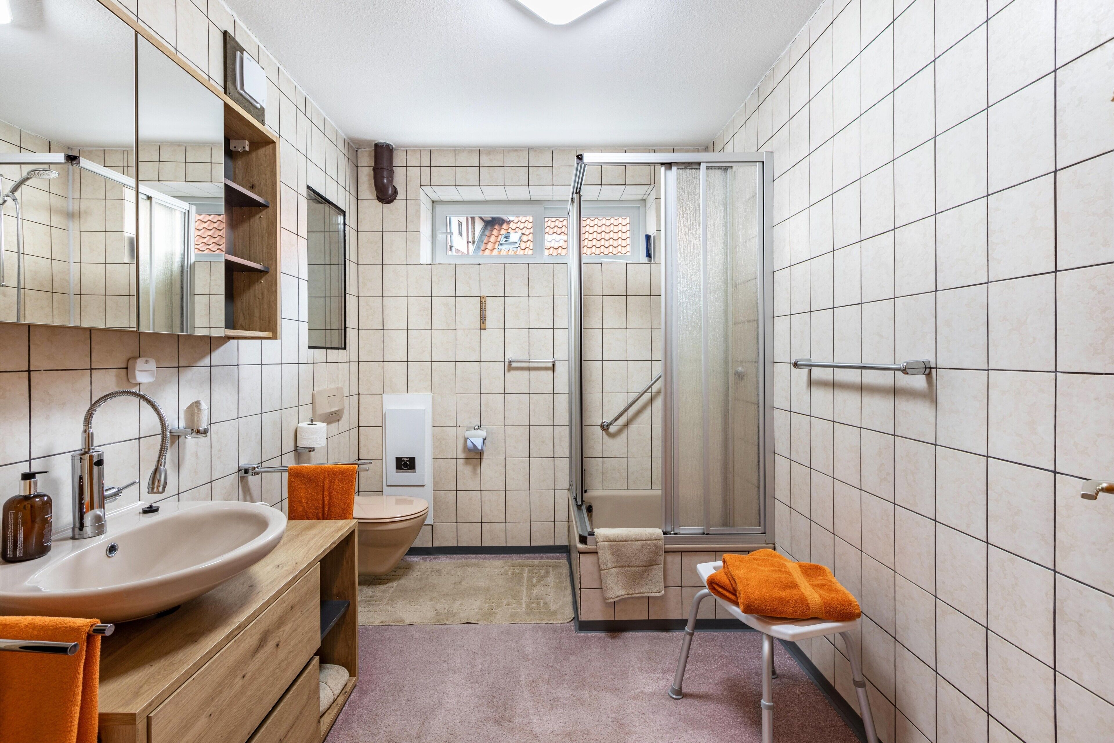 Ein Badezimmer mit Waschbecken, Spiegel, Dusche und Toilette.
