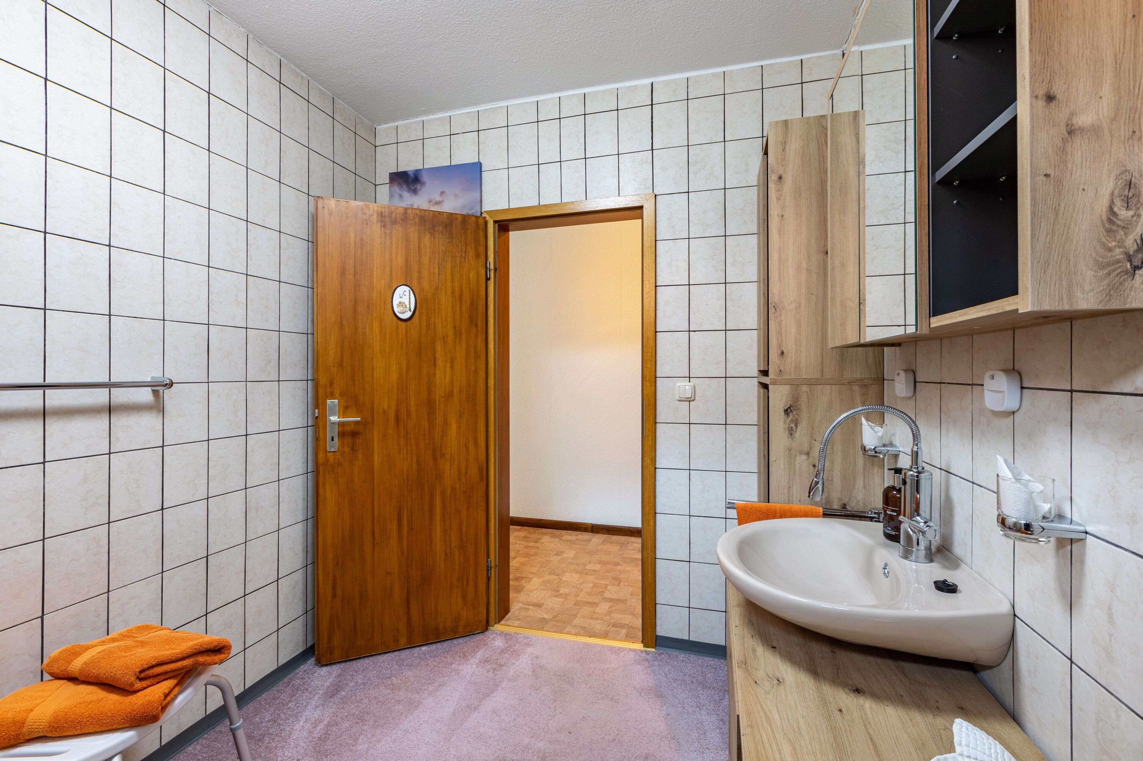 Un baño con puerta de madera, un lavabo y un perchero para toallas.