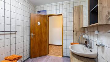 Un baño con puerta de madera, un lavabo y un perchero para toallas.
