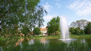 A tranquil pond with a central fountain, surrounded by lush greenery and a clear sky. - Apartment 'Haus Am Markt 3' with Private Terrace and Wi-Fi (Schöningen)
