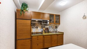 A compact kitchen with wooden cabinets, a microwave, and a sink. - Apartment 'Haus Am Markt 3' with Private Terrace and Wi-Fi (Schöningen)