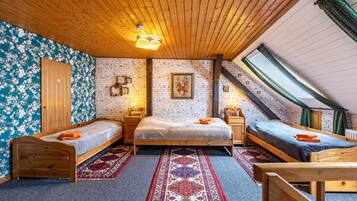 A loft bedroom with two wooden beds, a red and blue patterned rug, and a skylight.