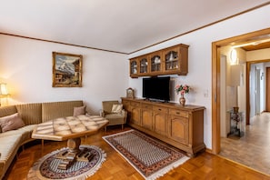 Un salon comprenant un canapé, une table basse, un téléviseur, des meubles en bois et un tableau accroché au mur.
