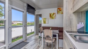 Une cuisine moderne avec un coin repas, de grandes fenêtres et des œuvres d’art accrochées aux murs.