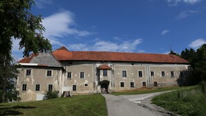 Un grand bâtiment historique, doté d’un toit recouvert de tuiles rouges et de nombreuses fenêtres.