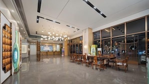 Een ruime lobby met een modern design, met een receptiebalie, een zithoek en grote ramen.