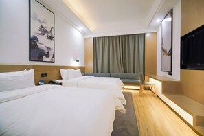 Habitación de hotel con dos camas, un sofá, un televisor y obras de arte en las paredes.