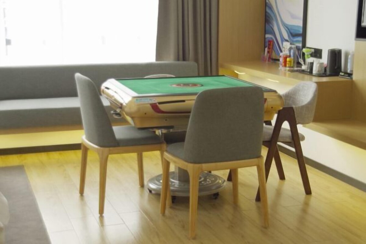 Una habitación con mesa de billar, dos sillas, un sofá y una ventana con cortinas.