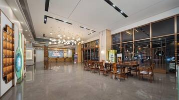 Un vestíbulo amplio con diseño moderno, que incluye una zona de recepción, asientos y grandes ventanales.