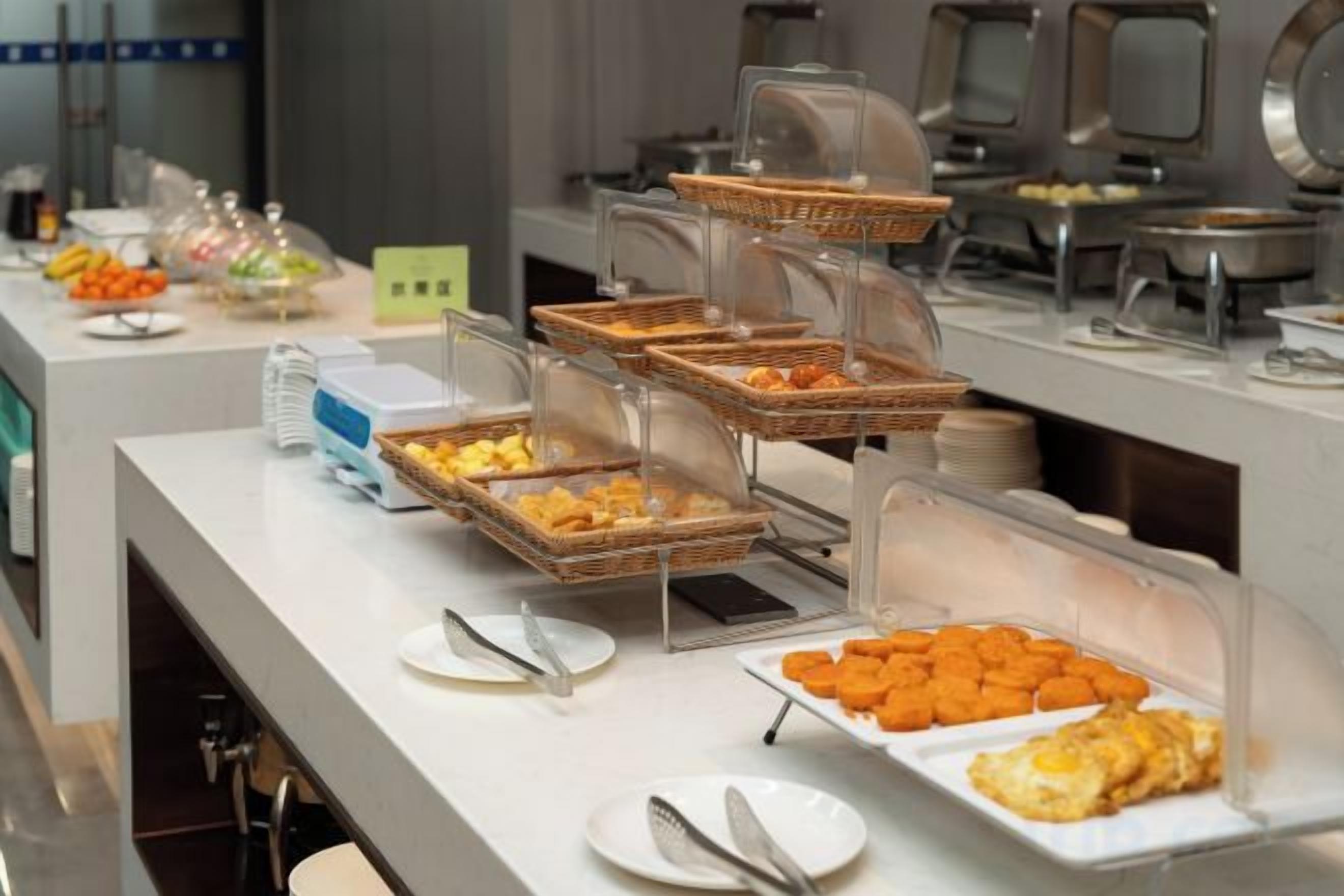 Un buffet avec différents plats présentés dans des récipients transparents.