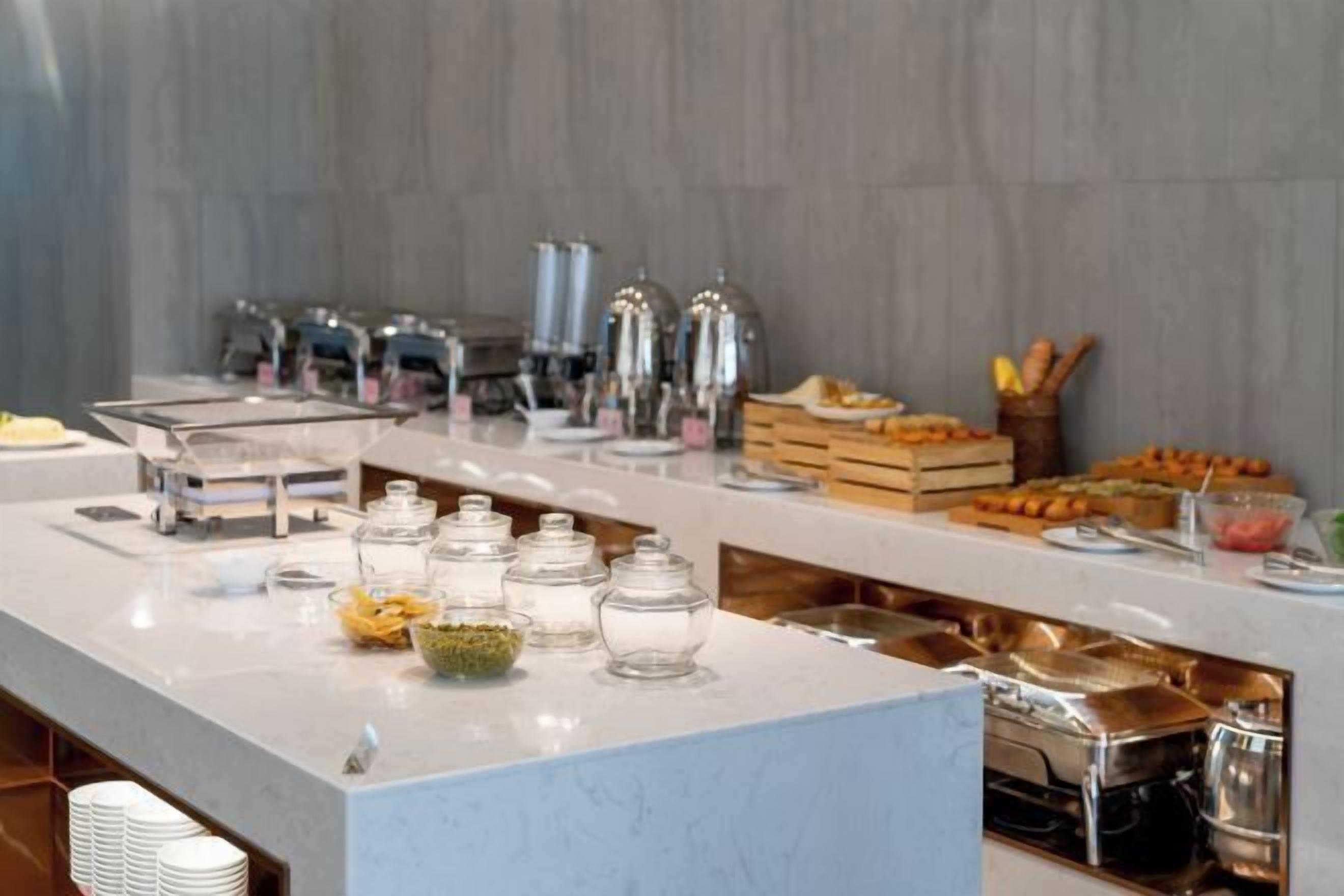 Una barra de buffet con distintos alimentos y salsas.