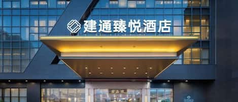 A hotel entrance with a modern facade, large windows, and a prominent sign.