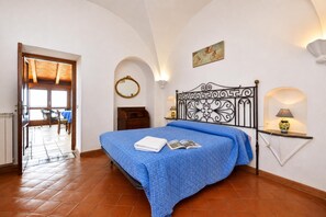 Une chambre à coucher comprenant un lit, une table de chevet, un miroir fixé au mur et une porte donnant sur un balcon.