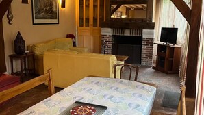 Una habitación acogedora con cama, chimenea, televisor y zona de comedor con mesa para dos.
