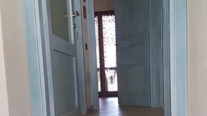 A hallway with light blue doors, a polished stone staircase, and a view into a room with a window. - House / Villa - Villasimius (Villasimius)