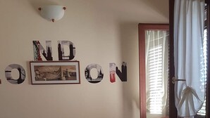 A room with a bed, a chair, a window with curtains, and wall decorations including the word "LONDON" and a picture of a bridge. - House / Villa - Villasimius (Villasimius)