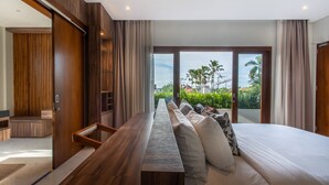 Una habitación de hotel moderna con una cama de madera grande, un sofá y vistas a palmeras y edificios.