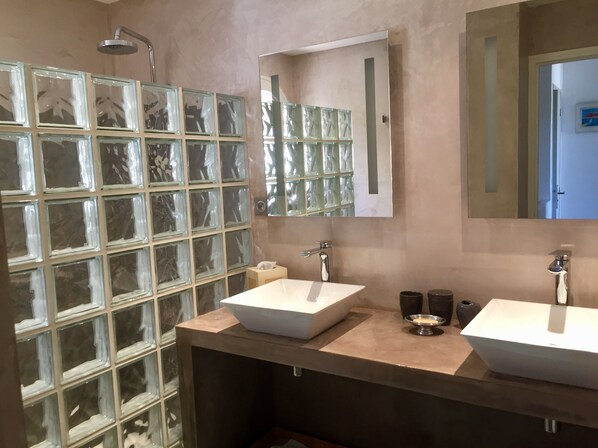 A bathroom with two sinks, a mirror, and a glass block wall.