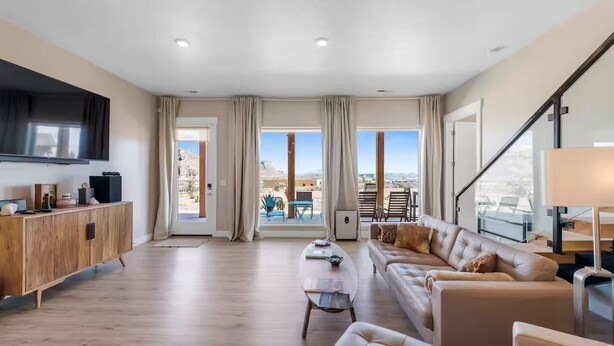 A spacious living room with a wooden cabinet, a leather sofa, and a flat-screen TV.