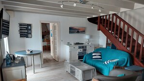 A cozy living room with a staircase, a dining area, and a view of the outside.