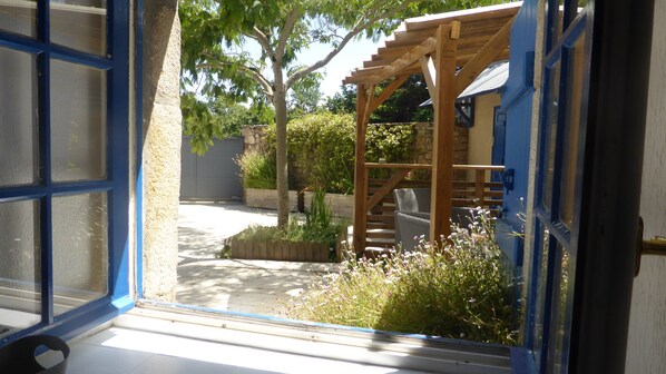 Una pérgola de madera, un muro de piedra y un jardín con diversas plantas y flores.