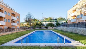 A rectangular swimming pool with a stone border, surrounded by well-maintained grass and a stone wall. - Apartment with terrace & pool 5min beach (Sant Feliu de Guíxols)