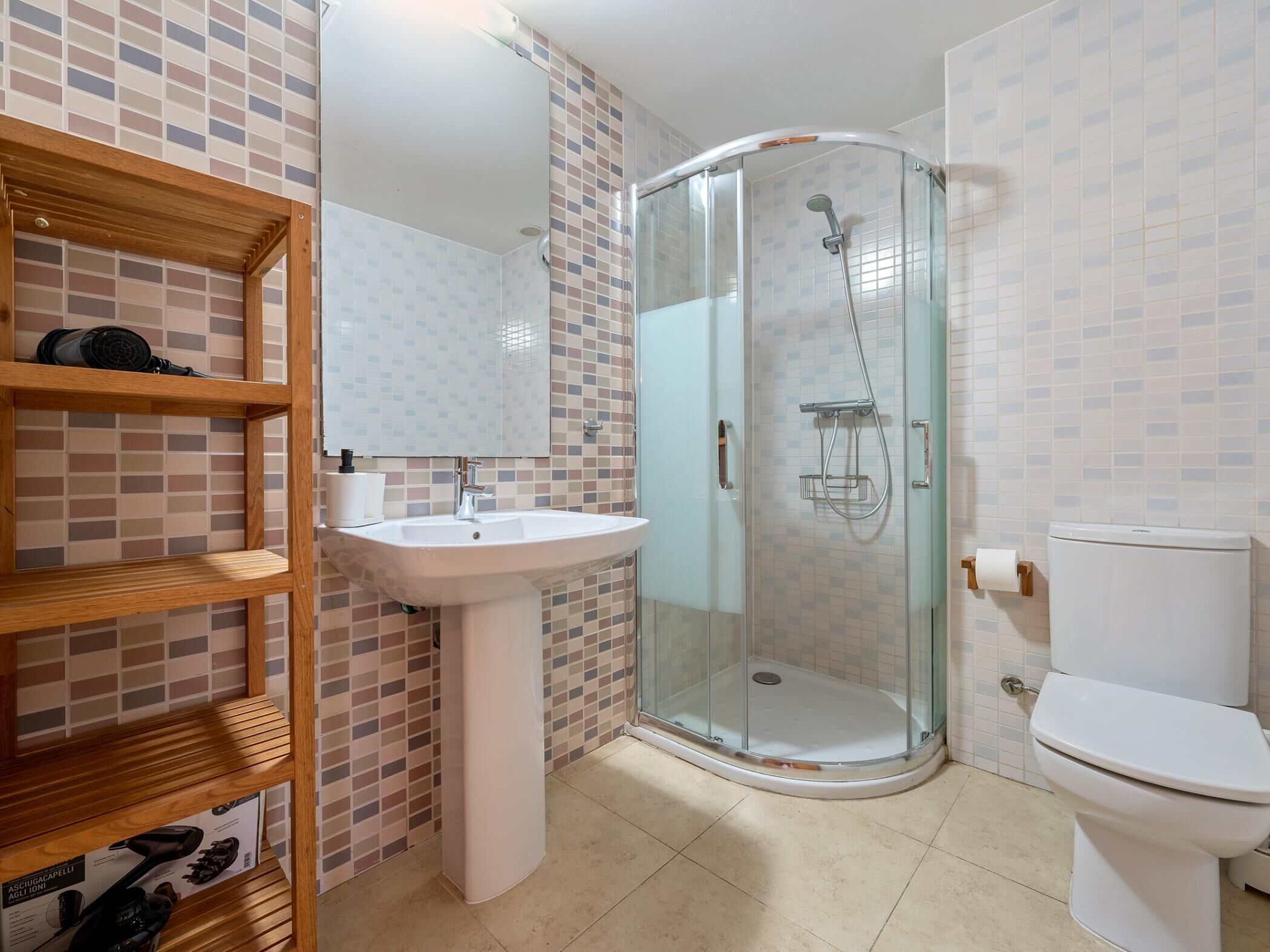 Un baño con cabina de ducha de vidrio, un lavamanos blanco y un inodoro.