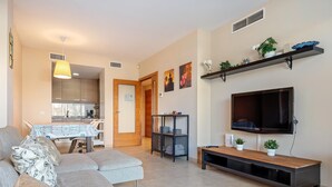 A modern living room with a sofa, TV, and shelves. - Apartment with terrace & pool 5min beach (Sant Feliu de Guíxols)