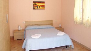 Een slaapkamer met een bed, twee nachtkastjes, een bedlampje en een schilderij aan de muur.