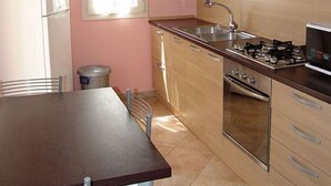 Een keuken met houten kastjes, een gasfornuis, een spoelbak en een raam.