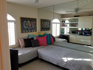 A bedroom with a large bed, a desk, and a TV.