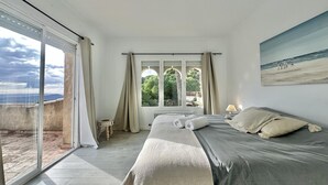 Une chambre à coucher avec un lit, une fenêtre avec des rideaux, un radiateur et une vue sur l’extérieur.