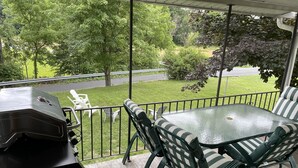 A covered outdoor patio with a glass-top table and striped green and white chairs.