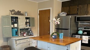 A kitchen with a wooden island, a bench, a refrigerator, and a stove.