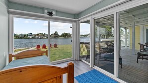 Un dormitorio con vista a un lago, una terraza de madera y mobiliario exterior.
