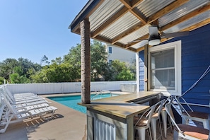 A poolside area with lounge chairs, a bar, and a pergola.