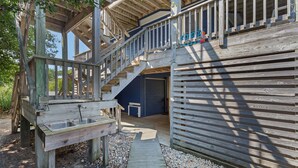 Een houten chalet met een trap naar een terras, een garagepoort en een klein zitgedeelte buiten.