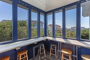 A corner room with large windows, wooden stools, and a metal ladder. - Happy Ours: Fun, Sun, Pool & Hot Tub in Corolla (Corolla)