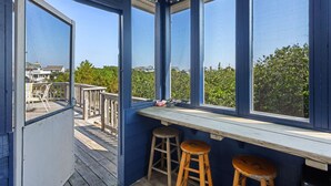 Een overdekt terras met uitzicht op zee en huizen.