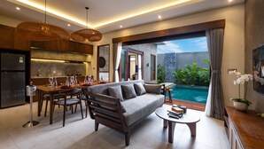 Un salon moderne comprenant un canapé, une table à manger et des chaises, un coin cuisine et une vue sur une piscine.